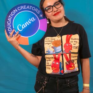 Smiling woman holding Canva sign on blue background, wearing graphic T-shirt.
