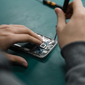 Menu A focused view of repairing a smartphone circuit board with tools by hand.